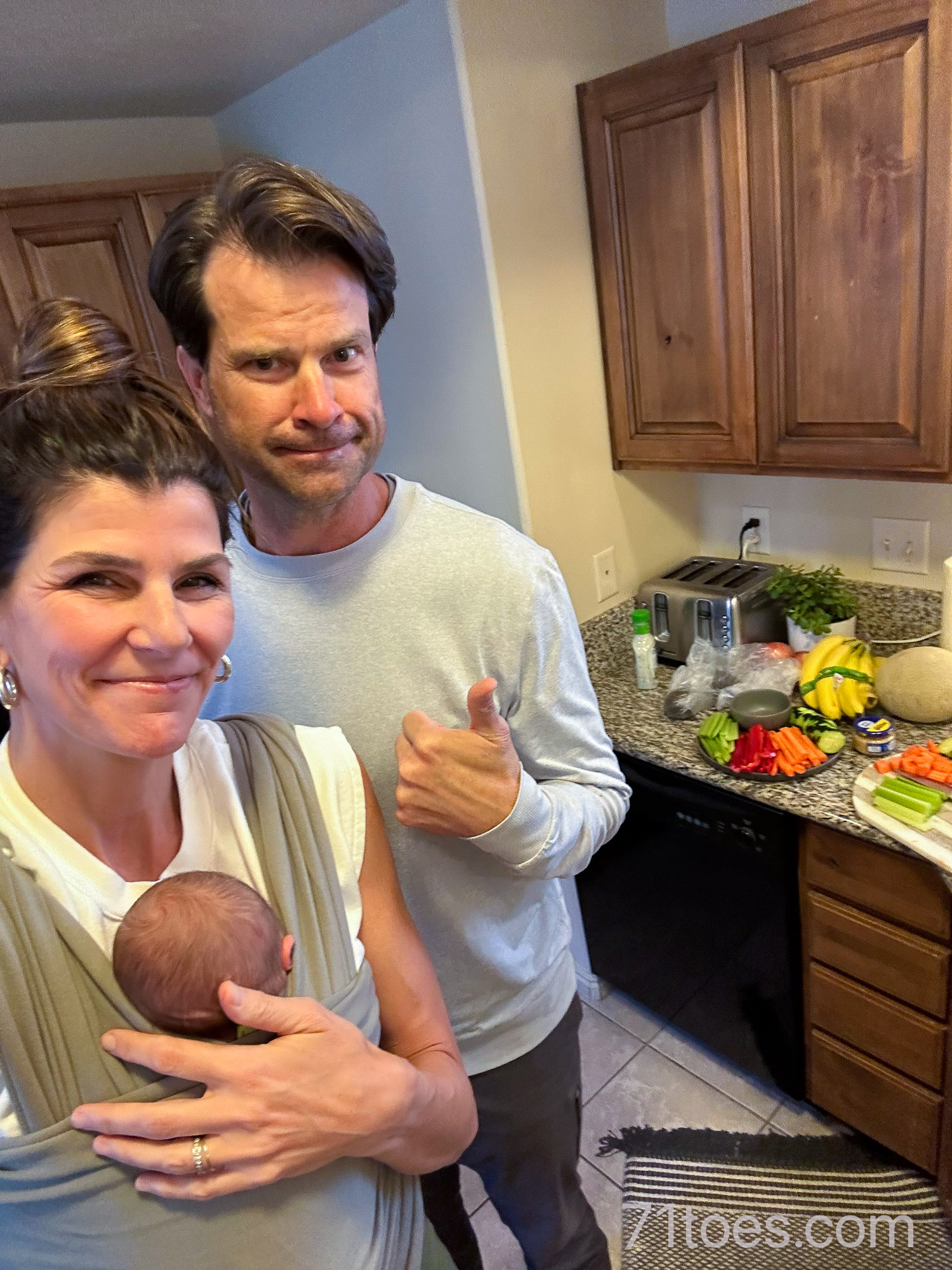 grandparents making dinner with grand-baby strapped on